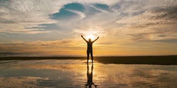 man with the arms in the air in front of ocean - self-acceptance 